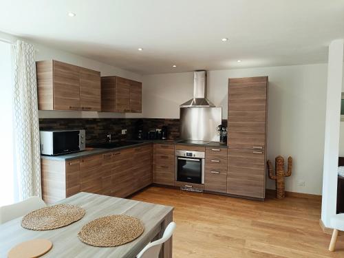 une cuisine avec des armoires en bois et une table avec des chaises dans l'établissement Normandie entre campagne et mer, à Émiéville