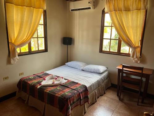 a bedroom with a bed with a chair and two windows at Beachside stay at Villa ViYarte in San Juan del Sur