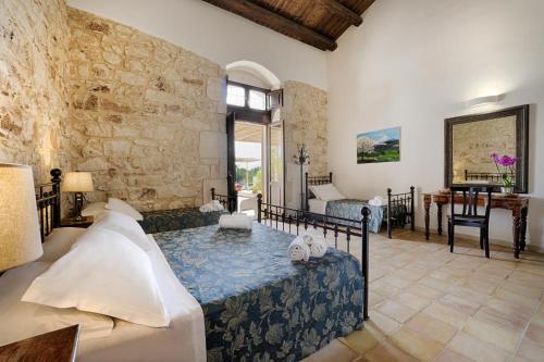 a bedroom with a bed and a stone wall at Baglio donna Concetta in Noto
