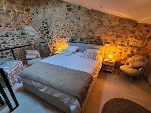 a bedroom with a bed in a room with stone walls at La Romarine in Chauzon