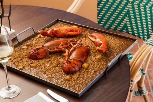 a tray with lobsters on a table with wine glasses at Hotel Sa Punta - Adults Only fr13 in Begur