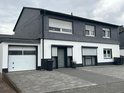 una casa bianca e nera con due porte garage di Ferienwohnung (T)raumland a Bad Berleburg