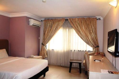 a bedroom with a bed and a desk and a window at Dino international Hotel in Ibadan