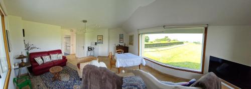 - un salon avec un canapé rouge et une grande fenêtre dans l'établissement Maison d'hôtes des marées du Guildo, à Saint-Cast-le-Guildo