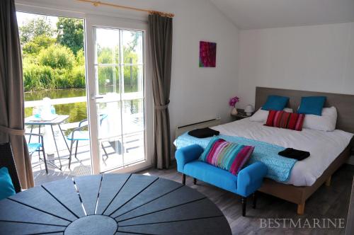a bedroom with a bed and a blue chair and a table at BestMarine Waterchalets Flevo Marina in Lelystad