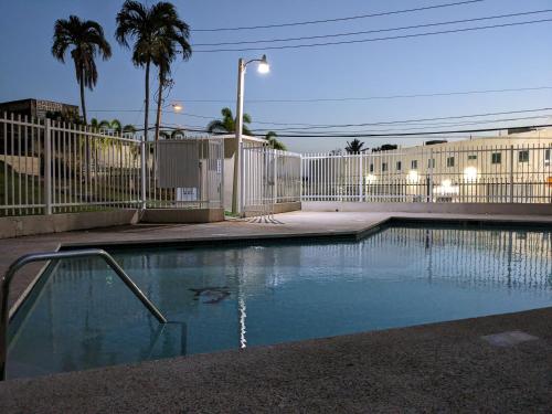een zwembad met een hek en palmbomen bij Private room and bathroom in large spacious 2 BR 2 BH in San Juan