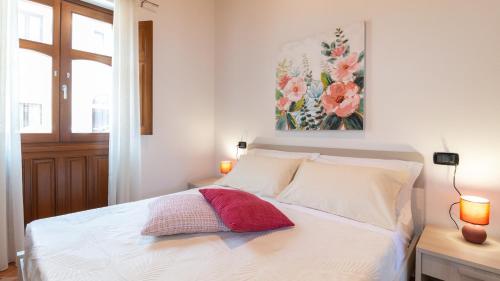 a bedroom with a white bed with a flower painting on the wall at Sardinianworld - Domo Mea in Càbras