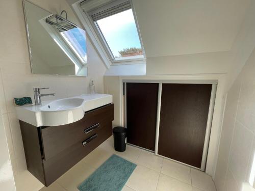 a bathroom with a sink and a mirror and a window at Maison Mboa in Fouesnant