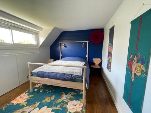 a bedroom with a bed with a blue wall at Maison Mboa in Fouesnant