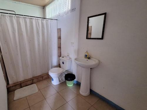 uma casa de banho com um WC branco e um lavatório. em Cabina Grande en Brasilito con piscina a 2 min caminando de playa brasilito em Brasilito