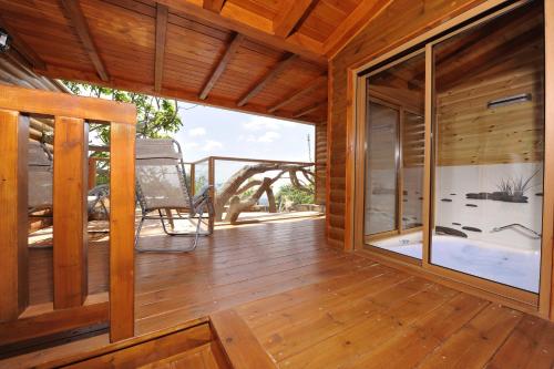 Habitación de madera con balcón y terraza con silla. en Ohn-Bar Guesthouse en Amirim