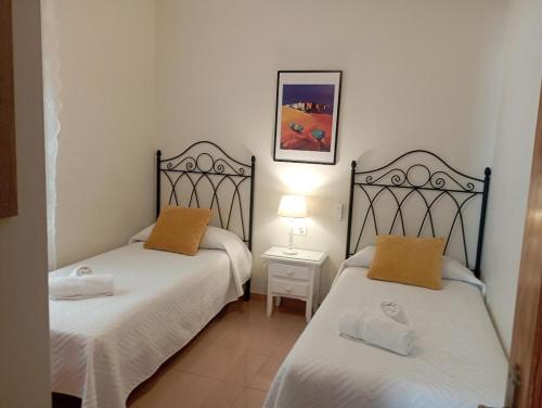 two beds in a small room with a lamp at Apartamento Con Vistas en Nerja in Nerja