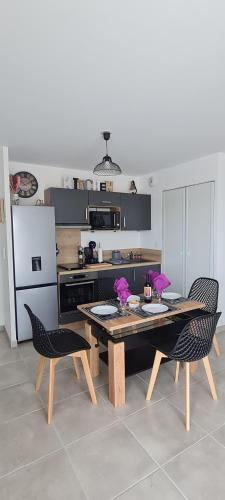 La cuisine est équipée d'une table, de deux chaises et d'un réfrigérateur. dans l'établissement Appartement SUNSET LODGE, à Narbonne-Plage