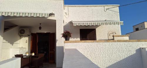 a white building with a door and a table on a balcony at Villetta Lorena a Mancaversa in Marina di Mancaversa