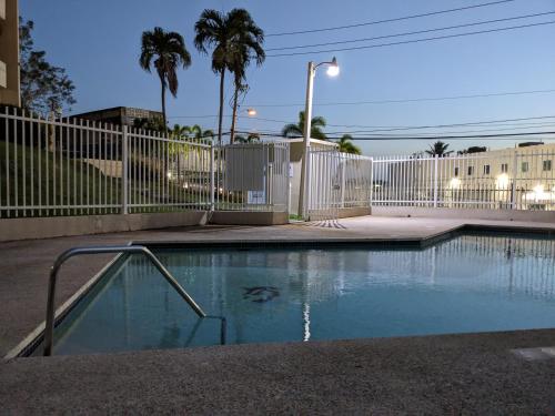 une piscine avec une clôture blanche et des palmiers dans l'établissement Spacious gated 2 bed 2 bath with pool, à San Juan