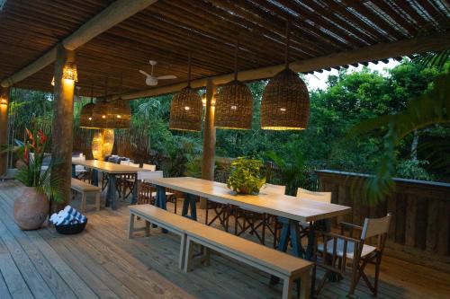 a restaurant with tables and chairs on a wooden deck at Santa Fe Casas Hotel Trancoso in Trancoso