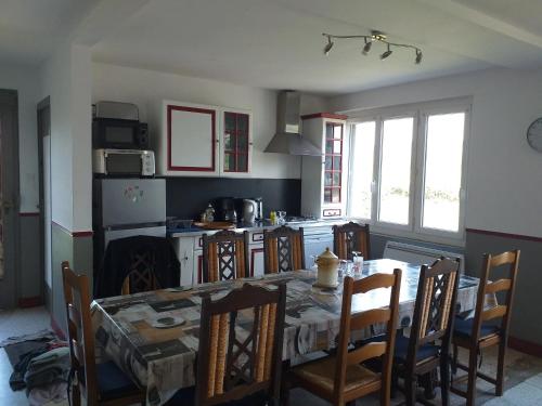 une cuisine avec une table et des chaises ainsi qu'une cuisine avec une cuisinière dans l'établissement Maison charmante à Villers-sous-Foucarmont avec jardin clôturé., à Villers-sous-Foucarmont