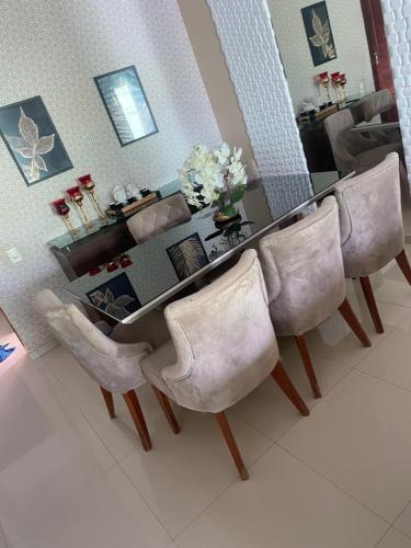 a dining room table with four white chairs and a mirror at Casa Grande com 2 quartos e 3 camas in Juazeiro do Norte