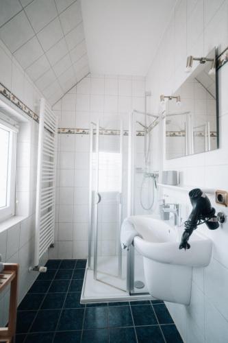 a white bathroom with a sink and a shower at Heimathafen in Büsum