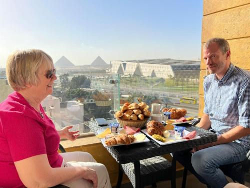 a man and a woman sitting at a table with food at Asia Grand Museum & Pyramids view in Cairo