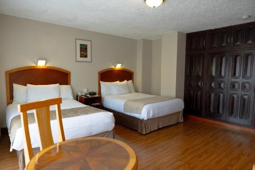 a hotel room with two beds and a table at Hotel Santa Monica in Cuenca