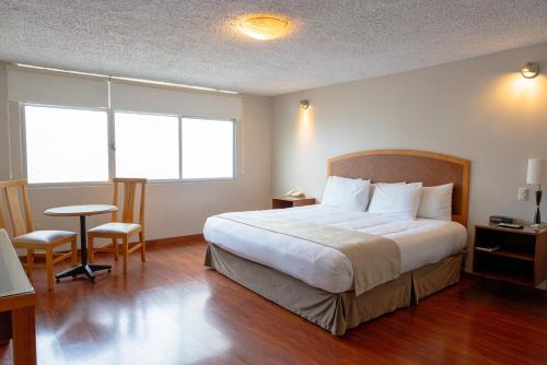 a hotel room with a bed and a table and chairs at Hotel Santa Monica in Cuenca