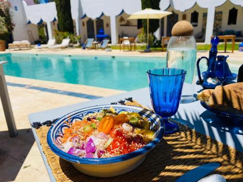 un tazón de comida sentado en una mesa junto a una piscina en L' Ecrin de Mogador Essaouira, en Ounara