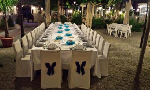 a long table with white chairs and tables with bows at Residence Regina in Marina di Gioiosa Ionica