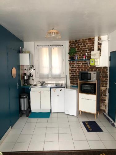 - une cuisine avec des appareils blancs et un mur en briques dans l'établissement Au coeur du 18eme arrondissement proche de Montmarte et des Jeux Olympiques, à Paris