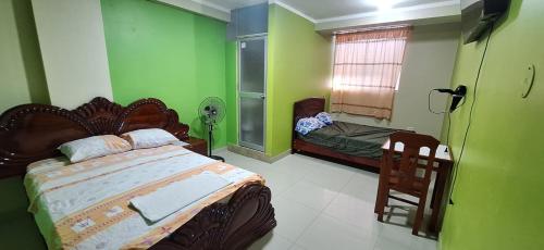 1 dormitorio con paredes verdes, 1 cama y 1 silla en HOSPEDAJE EL CANTARO II en Tingo María