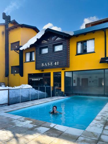 a person swimming in a swimming pool in front of a building at Complejo Base 41 in San Carlos de Bariloche