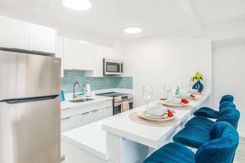 a white kitchen with blue chairs and a table at Newly Renovated 2 Bedroom Condo, 1 Block to Waikiki Beach, Free Parking in Honolulu