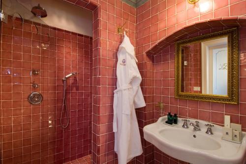 un bagno piastrellato rosso con lavandino e specchio di Villa la Borghetta Spa Resort a Figline Valdarno