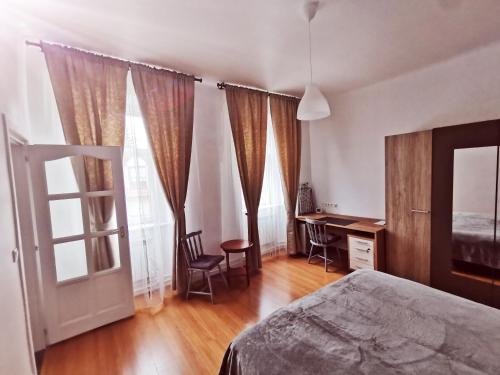 Un dormitorio con cama, escritorio y ventanas en CLA Group Apartment, en Sopron