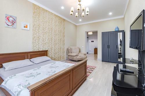 a bedroom with a bed and a tv and a chair at Светлая квартира in Zaozërnyy