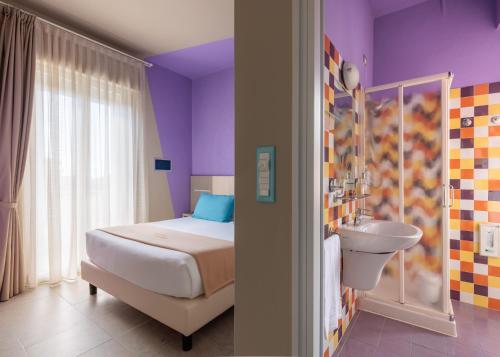 マリーナ・ディ・ビッボーナにあるHotel Ninaのベッドルーム(ベッド1台、シンク、トイレ付)