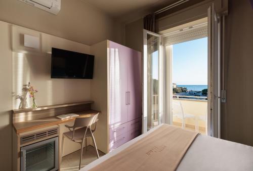 een slaapkamer met een bed, een bureau en een raam bij Hotel Nina in Marina di Bibbona