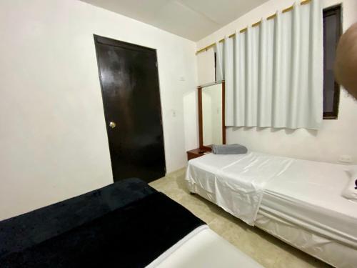 a bedroom with two beds and a black door at Apartamento cerca del aeropuerto in Cartagena de Indias