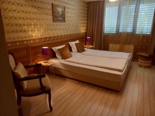 a bedroom with a large bed and a chair at Hotel Rio in Nova Zagora