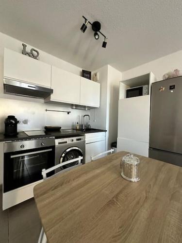 Il comprend une cuisine avec une table en bois et des appareils électroménagers. dans l'établissement Le Lironde - charmant F2, à Montpellier