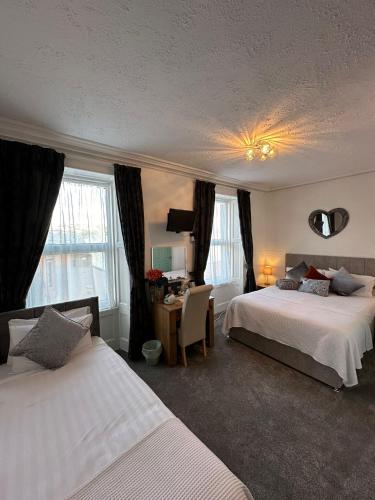 a bedroom with two beds and a desk and windows at Abbey House B & B in Penrith