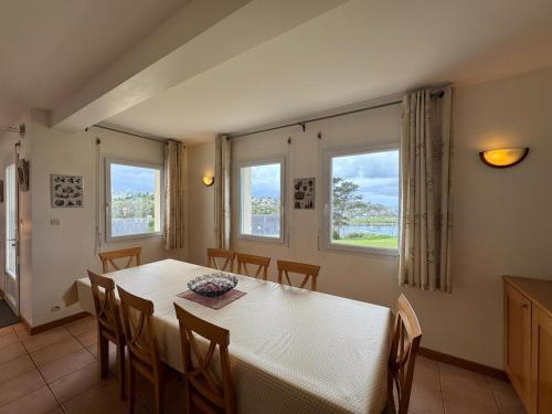 comedor con mesa, sillas y 2 ventanas en Grande villa de 265m2 vue mer imprenable 11 à 12 personnes en Landéda