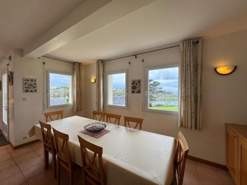 une salle à manger avec une table et des chaises et deux fenêtres dans l'établissement Grande villa de 265m2 vue mer imprenable 11 à 12 personnes, à Landéda