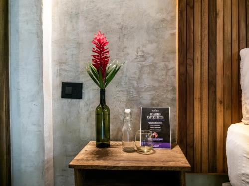 a red flower in a bottle on a table at Salvia Madre Hotel Boutique in Guachaca