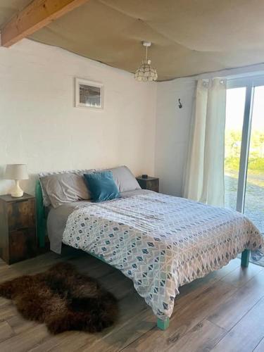 a bedroom with a bed with a comforter on it at Clarefornia Stone Shed in Lahinch