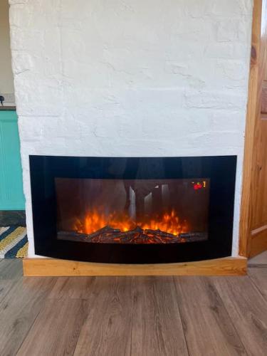 a fireplace in a living room with flames in it at Clarefornia Stone Shed in Lahinch