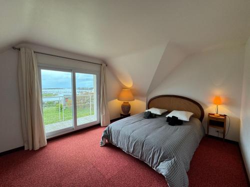 une chambre avec un lit et une grande fenêtre dans l'établissement Grande villa de 265m2 vue mer imprenable 11 à 12 personnes, à Landéda