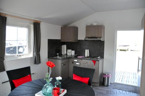 a kitchen with a table and a kitchen with red chairs at BestMarine Waterchalets Flevo Marina in Lelystad