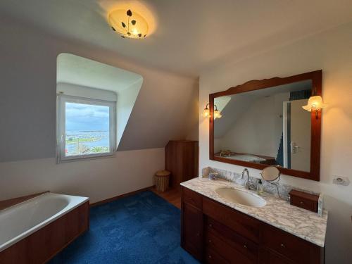 y baño con bañera, lavabo y espejo. en Grande villa de 265m2 vue mer imprenable 11 à 12 personnes en Landéda