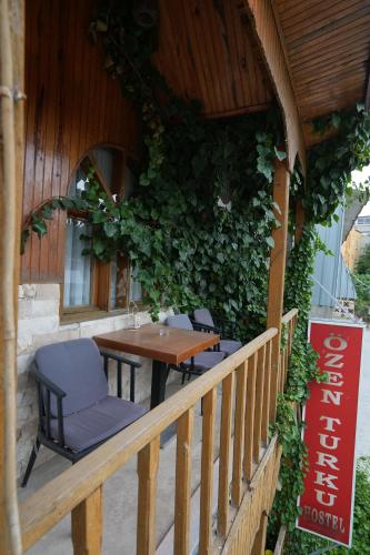 a table and chairs on a porch with a green wall at OzenTurku Hotel in Pamukkale